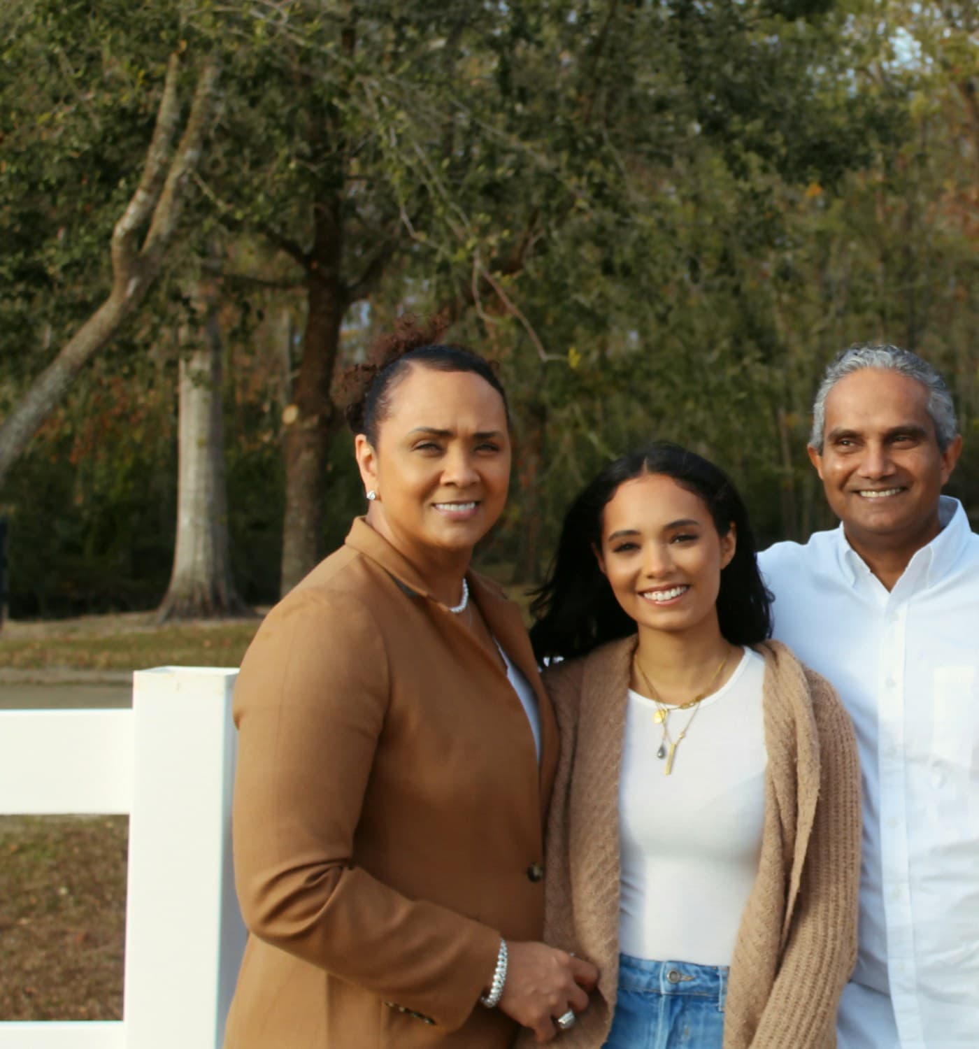 A young woman standing between two supportive parents